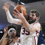 
              Oklahoma forward Tanner Groves reaches for a rebound in front of teammate Jalen Hill, left, and Kansas City forward Promise C. Idiaru, right, in the first half of an NCAA college basketball game, Tuesday, Dec. 6, 2022, in Norman, Okla. (AP Photo/Sue Ogrocki)
            