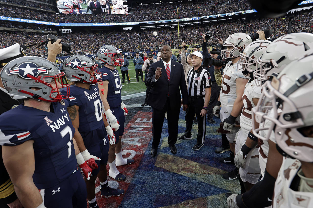 FILE - Defense Secretary Lloyd Austin flips the coin before the first half of an NCAA college footb...