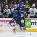 
              Vancouver Canucks' Kyle Burroughs (44) checks Seattle Kraken's Brandon Tanev, back, during the second period of an NHL hockey game Thursday, Dec. 22, 2022, in Vancouver, British Columbia. (Darryl Dyck/The Canadian Press via AP)
            