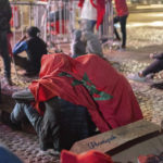 
              Moroccans draped in the country flag to shelter from rain react as they watch the World Cup semifinal soccer match between France and Morocco played in Qatar, at a public viewing place in Rabat, Morocco, Wednesday, Dec. 14, 2022. (AP Photo/Sonia Moussaid)
            