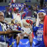 
              FILE - Fans of France cheer prior to the World Cup group D soccer match between France and Denmark at the Stadium 974 in Doha, Qatar, Saturday, Nov. 26, 2022.  At a World Cup that has become a political lightning rod, it comes as no surprise that soccer fans’ sartorial style has sparked controversy. At the first World Cup in the Middle East, fans from around the world have refashioned traditional Gulf Arab headdresses and thobes. (AP Photo/Martin Meissner, File)
            