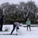 
              A family build a snowman in London, Monday, Dec. 12, 2022. Snow and ice have swept across parts of the UK, with cold wintry conditions set to continue for days. (AP Photo/Kin Cheung)
            