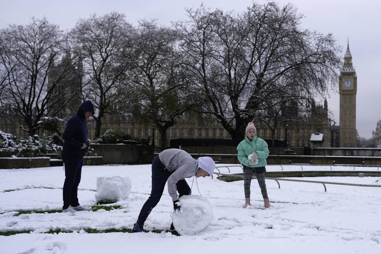 A family build a snowman in London, Monday, Dec. 12, 2022. Snow and ice have swept across parts of ...