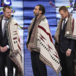 
              Former Vancouver Canucks players  Henrik Sedin, left, goalie Roberto Luongo, center, and Daniel Sedin stand after being wrapped in First Nations blankets during a ceremony honoring their recent inductions into the Hockey Hall of Fame, before an NHL hockey game between the Canucks and the Florida Panthers on Thursday, Dec. 1, 2022, in Vancouver, British Columbia. (Darryl Dyck/The Canadian Press via AP)
            
