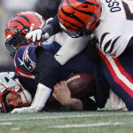 
              New England Patriots quarterback Mac Jones, left, holds the ball as he hits the ground while Cincinnati Bengals defensive end Joseph Ossai, right, defends during the second half of an NFL football game, Saturday, Dec. 24, 2022, in Foxborough, Mass. (AP Photo/Michael Dwyer)
            