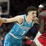 
              Charlotte Hornets guard LaMelo Ball, left, dribbles past Portland Trail Blazers forward Jerami Grant during the first half of an NBA basketball game in Portland, Ore., Monday, Dec. 26, 2022. (AP Photo/Craig Mitchelldyer)
            