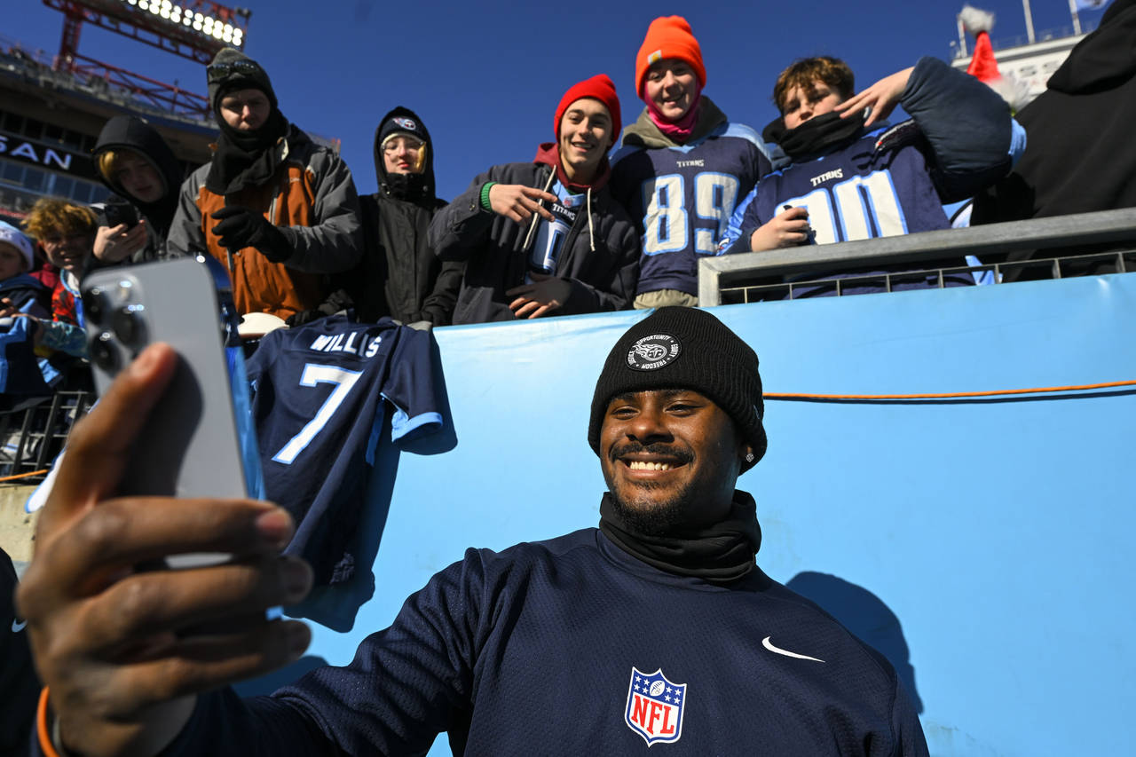 Tennessee Titans quarterback Malik Willis takes a photo with fans before an NFL football game betwe...