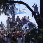 
              Soccer fans wave at players on an open-top bus carrying the Argentine national soccer team that won the World Cup title in Buenos Aires, Argentina, Tuesday, Dec. 20, 2022. (AP Photo/Natacha Pisarenko)
            