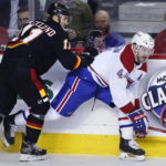 
              Montreal Canadiens' Joel Edmundson, right, takes a check from Calgary Flames' Mikael Backlund during first-period NHL hockey game action in Calgary, Alberta, Thursday, Dec. 1, 2022. (Larry MacDougal/The Canadian Press via AP)
            