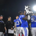 
              Duke offensive lineman Jacob Monk (63), defensive tackle DeWayne Carter (90) and quarterback Riley Leonard (13) hold the Military Bowl trophy as head coach Mike Elko, left, cheers after the Military Bowl NCAA college football game against UCF, Wednesday, Dec. 28, 2022, in Annapolis, Md. (AP Photo/Terrance Williams)
            