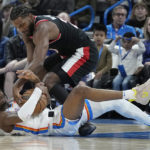 
              Portland Trail Blazers forward Justise Winslow, top, reaches for the ball held by Oklahoma City Thunder guard Shai Gilgeous-Alexander, bottom, in the first half of an NBA basketball game Monday, Dec. 19, 2022, in Oklahoma City. (AP Photo/Sue Ogrocki)
            
