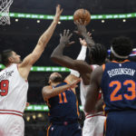 
              New York Knicks' Jalen Brunson (11) goes up to shoot against Chicago Bulls' Nikola Vucevic (9) and Patrick Williams (44) during the first half of an NBA basketball game Friday, Dec. 16, 2022, in Chicago. (AP Photo/Paul Beaty)
            