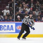 
              Linesman Trent Knorr picks up a Vancouver Canucks jersey that was thrown onto the ice by a fan as Vancouver and the Winnipeg Jets play during the third period of an NHL hockey game, Saturday, Dec. 17, 2022 in Vancouver, British Columbia. (Darryl Dyck/The Canadian Press via AP)
            