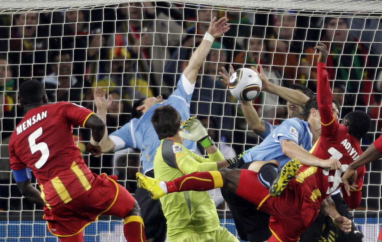 FILE - Uruguay's Luis Suarez, right, stops the ball with his hands to give away a penalty kick duri...