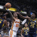 
              Atlanta Hawks' John Collins (20) reaches for a rebound between Indiana Pacers' Myles Turner (33) and Aaron Nesmith (23) during the first half of an NBA basketball game Tuesday, Dec. 27, 2022, in Indianapolis. (AP Photo/Darron Cummings)
            