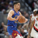 
              Denver Nuggets forward Michael Porter Jr., left, passes the ball as Portland Trail Blazers guard Anfernee Simons defends in the first half of an NBA basketball game Friday, Dec. 23, 2022, in Denver. (AP Photo/David Zalubowski)
            