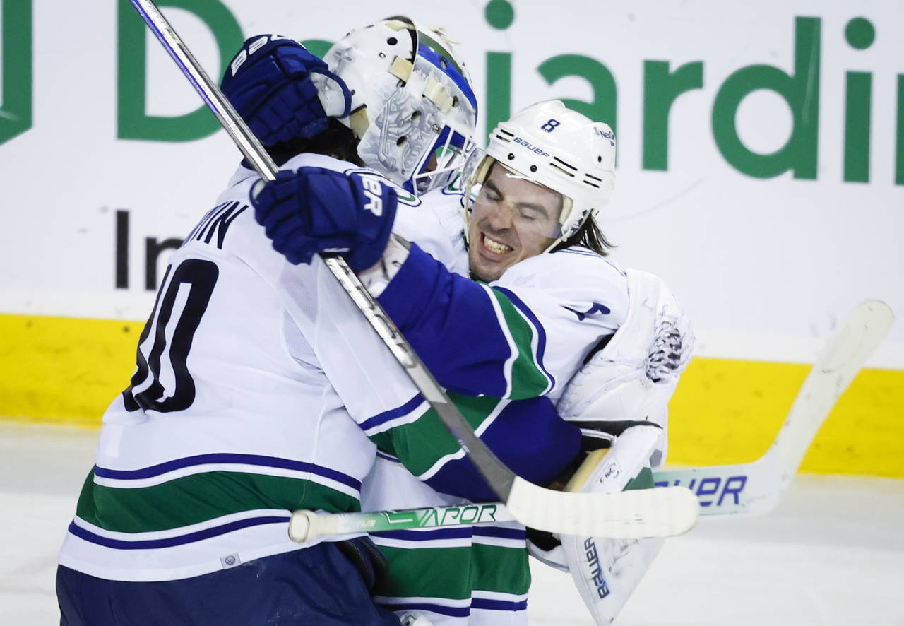 Vancouver Canucks goalie Spencer Martin, left, and forward Conor Garland celebrate defeating the Ca...