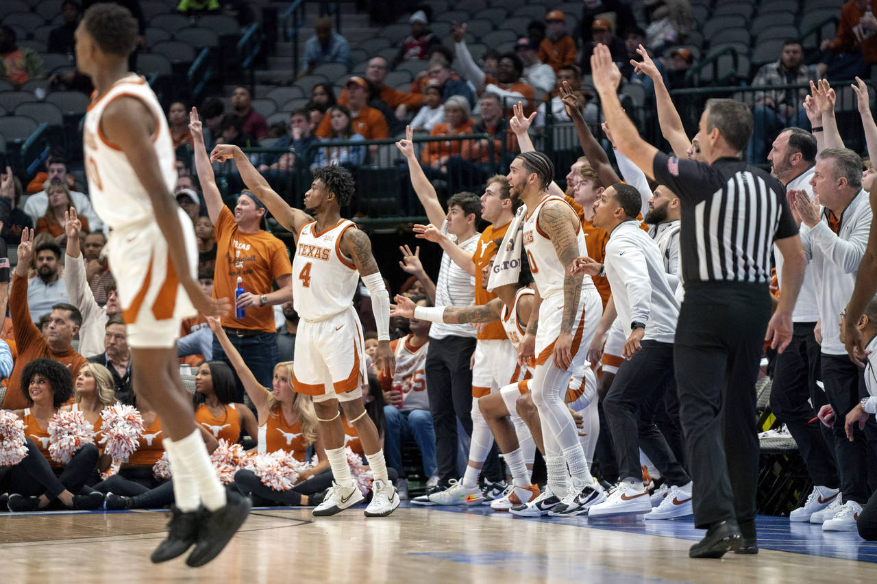 Texas guard Tyrese Hunter (4) and the Texas bench watch the flight of Hunter's 3-pointer during the...