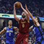 
              Cleveland Cavaliers forward Kevin Love (0) shoots against Orlando Magic forwards Franz Wagner (22) and Caleb Houstan (2) during the first half of an NBA basketball game, Friday, Dec. 2, 2022, in Cleveland. (AP Photo/Ron Schwane)
            