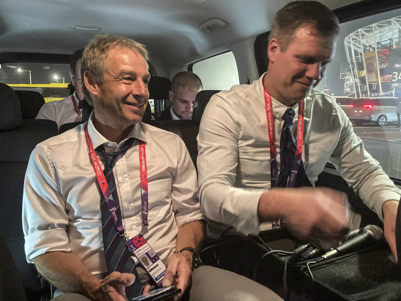 Juergen Klinsmann, left, sits in a car as he records a podcast after the World Cup group C soccer m...