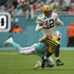 
              Green Bay Packers quarterback Aaron Rodgers (12) runs through a tackle by Miami Dolphins linebacker Jaelan Phillips (15) as he runs with the ball during the first half of an NFL football game, Sunday, Dec. 25, 2022, in Miami Gardens, Fla. (AP Photo/Jim Rassol)
            