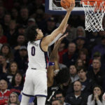 
              Gonzaga guard Julian Strawther (0) shoots while defended by Washington forward Keion Brooks (1) during the first half of an NCAA college basketball game, Friday, Dec. 9, 2022, in Spokane, Wash. (AP Photo/Young Kwak)
            