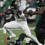 
              Jacksonville Jaguars running back Travis Etienne Jr. (1) almost fumbles the ball while avoiding New York Jets cornerback Michael Carter II (30) during the first quarter of an NFL football game, Thursday, Dec. 22, 2022, in East Rutherford, N.J. (AP Photo/Seth Wenig)
            