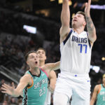 
              Dallas Mavericks' Luka Doncic (77) goes to the basket against San Antonio Spurs' Zach Collins during the first half of an NBA basketball game Saturday, Dec. 31, 2022, in San Antonio. (AP Photo/Darren Abate)
            