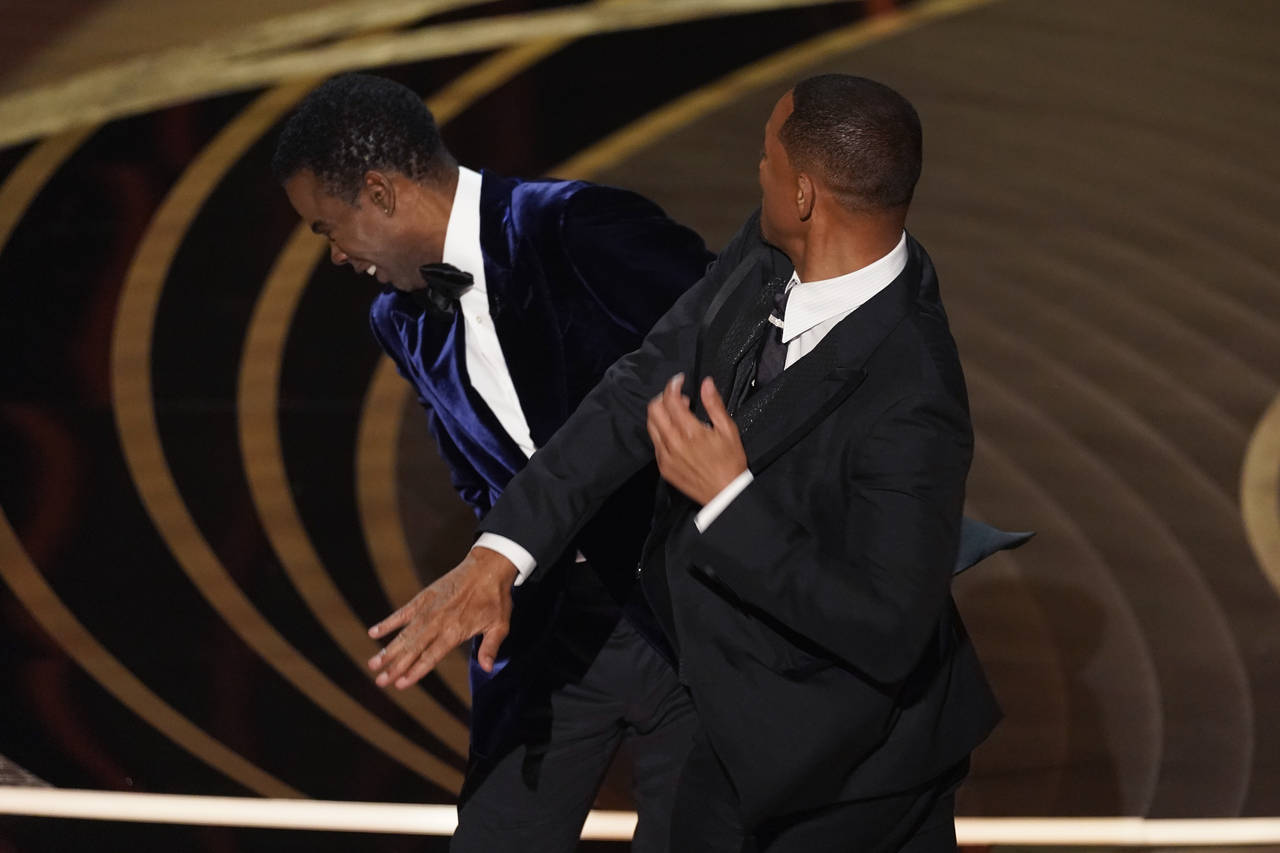 Will Smith, right, hits presenter Chris Rock on stage while presenting the award for best documenta...