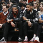 
              Colin Kaepernick, center left, sits beside Akim Aliu as they watch the Toronto Raptors take on the Boston Celtics in an NBA basketball game in Toronto, Monday, Dec. 5, 2022. (Chris Young/The Canadian Press via AP)
            