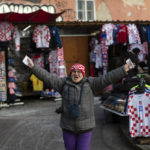 
              A woman wearing a checkered hat in the colors of the Croatian coat of arms cheers as she walks through a market ahead of the national team's Qatar World Cup soccer semifinal match against Argentina, in Zagreb, Croatia, Tuesday, Dec. 13, 2022. (AP Photo/Marko Drobnjakovic)
            
