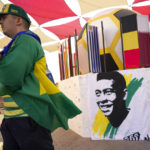 
              A fan walks past a portrait of Pelé displayed at a Brazilian fan party before the the World Cup round of 16 soccer match between Brazil and South Korea, in Doha, Dec. 5, 2022. The 82-year-old Pelé remained in a hospital in San Paulo recovering from a respiratory infection that was aggravated by COVID-19, but the news coming from Brazil early Monday was good. (AP Photo/Ashley Landis)
            