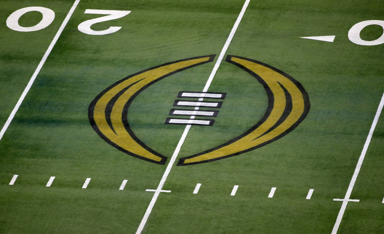 FILE - The College Football Playoff logo is shown on the field at AT&T Stadium before the Rose Bowl...