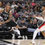 
              San Antonio Spurs' Jeremy Sochan (10) dives ahead of Portland Trail Blazers' Anfernee Simons to keep the ball in bounds during the second half of an NBA basketball game, Wednesday, Dec. 14, 2022, in San Antonio. (AP Photo/Darren Abate)
            