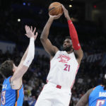 
              Philadelphia 76ers center Joel Embiid (21) shoots between Oklahoma City Thunder center Mike Muscala, left, and guard Luguentz Dort, right, in the first half of an NBA basketball game Saturday, Dec. 31, 2022, in Oklahoma City. (AP Photo/Sue Ogrocki)
            
