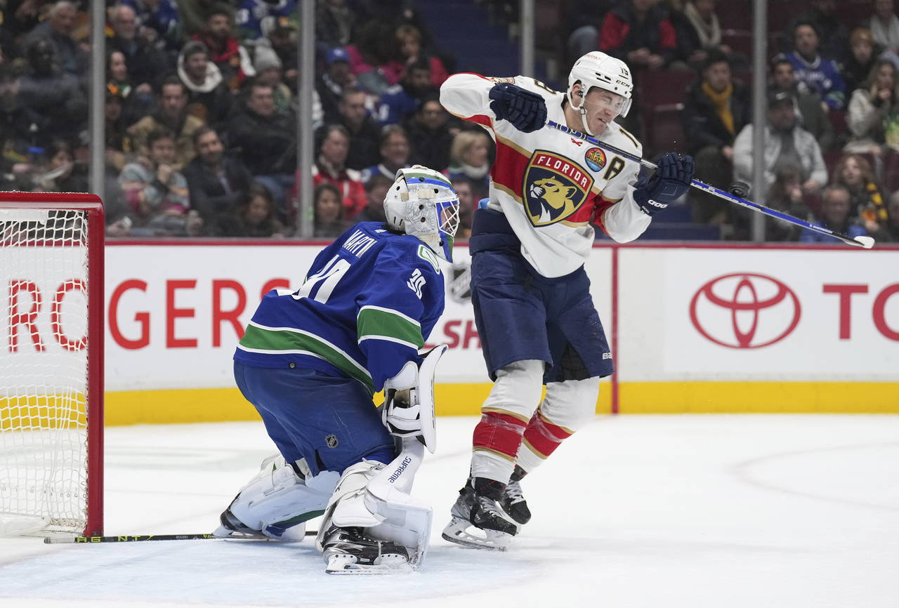 Florida Panthers' Matthew Tkachuk, right, deflects the puck wide of the net behind Vancouver Canuck...