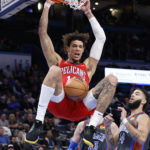 
              New Orleans Pelicans center Jaxson Hayes, top, dunks while Oklahoma City Thunder center Mike Muscala and forward Kenrich Williams look on during the second half of an NBA basketball game Friday, Dec. 23, 2022, in Oklahoma City. (AP Photo/Garett Fisbeck)
            