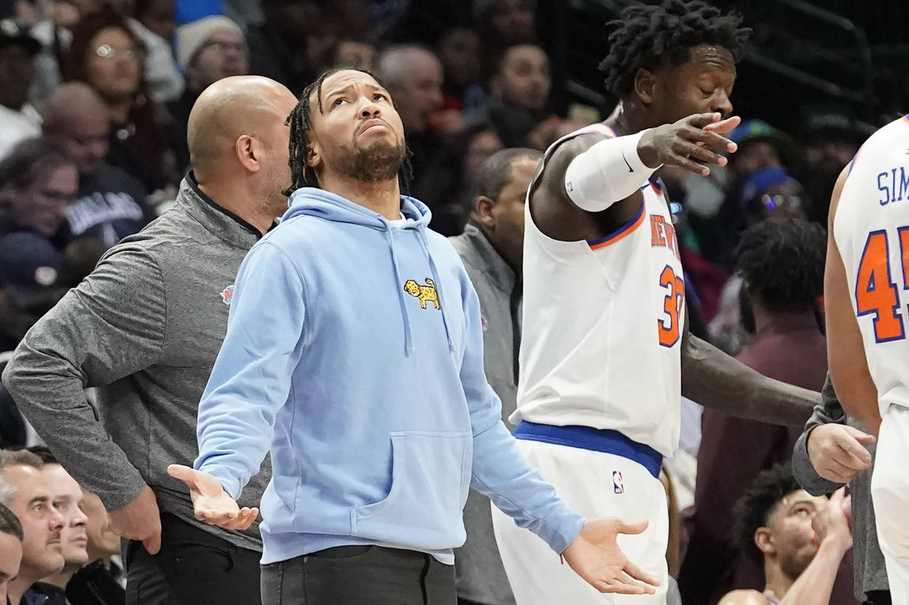 New York Knicks Jalen Brunson, left, gestures as he looks up from the sidelines during a timeout du...