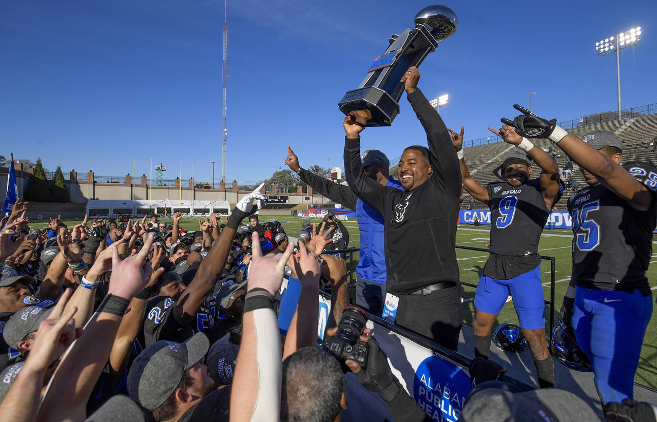 Buffalo head coach Maurice Linguist lifts the Camellia Bowl Trophy in front of his team after they ...