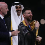 
              Argentina's Lionel Messi holds up the trophy flanked by FIFA President Gianni Infantino and The Emir of Qatar Sheikh Tamim bin Hamad Al Thani after winning the World Cup final soccer match between Argentina and France at the Lusail Stadium in Lusail, Qatar, Sunday, Dec.18, 2022. (AP Photo/Manu Fernandez)
            