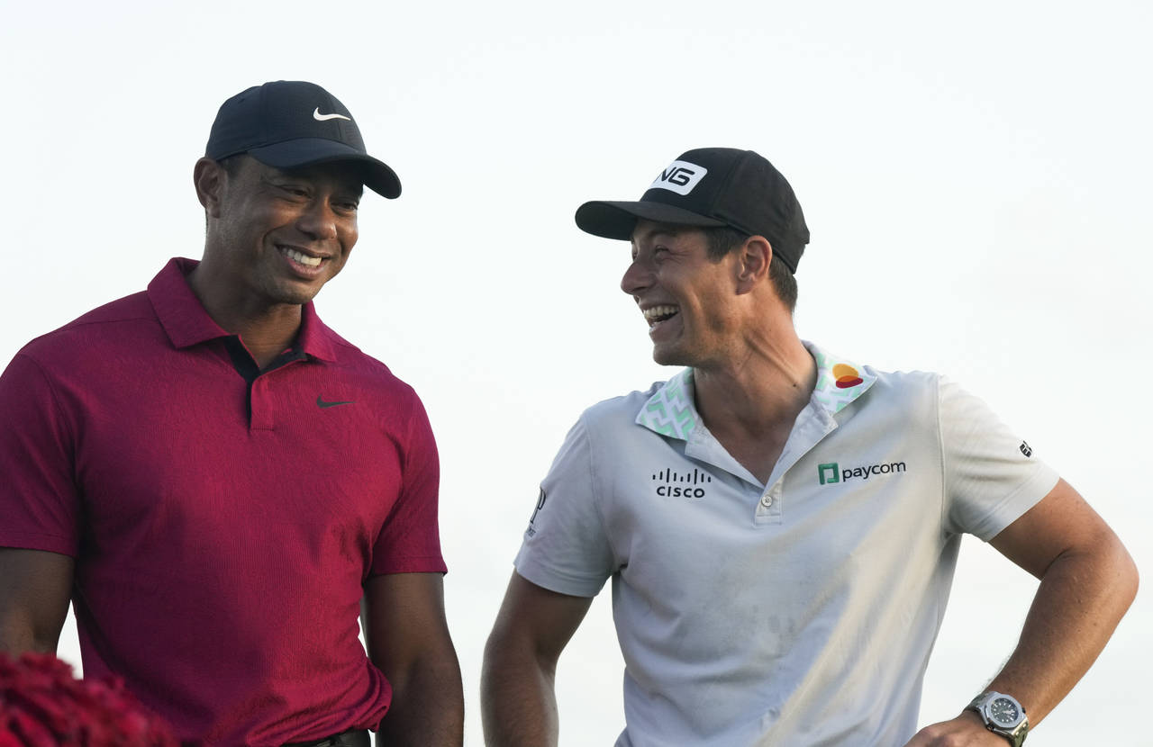 Viktor Hovland, of Norway, right, shares a laugh with Tiger Woods, after winning the Hero World Cha...