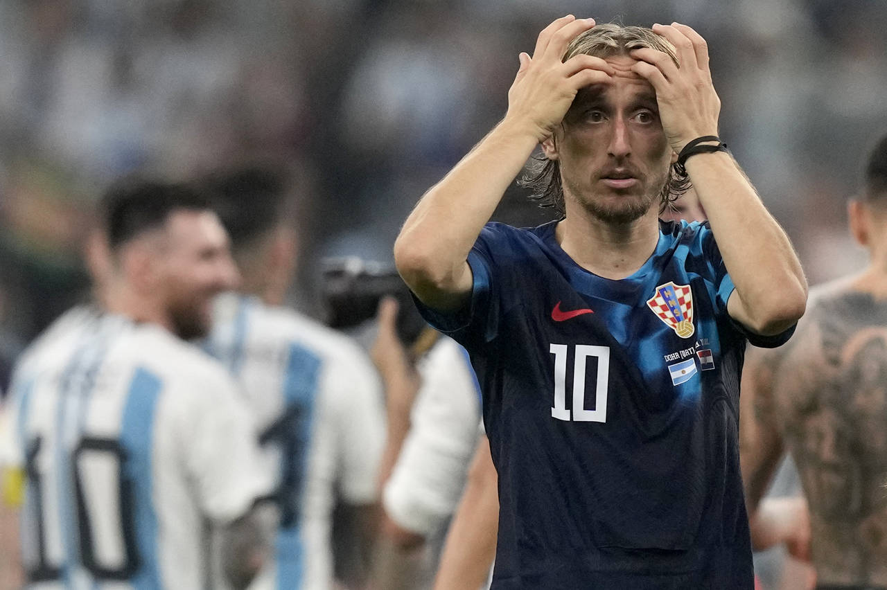 Croatia's Luka Modric reacts, while Argentina's Lionel Messi, background left, celebrates, at the e...