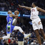 
              Milwaukee Bucks guard Jevon Carter (5) passes the ball as Cleveland Cavaliers forward Evan Mobley (4) defends during the first half of an NBA basketball game Wednesday, Dec. 21, 2022, in Cleveland. (AP Photo/Ron Schwane)
            
