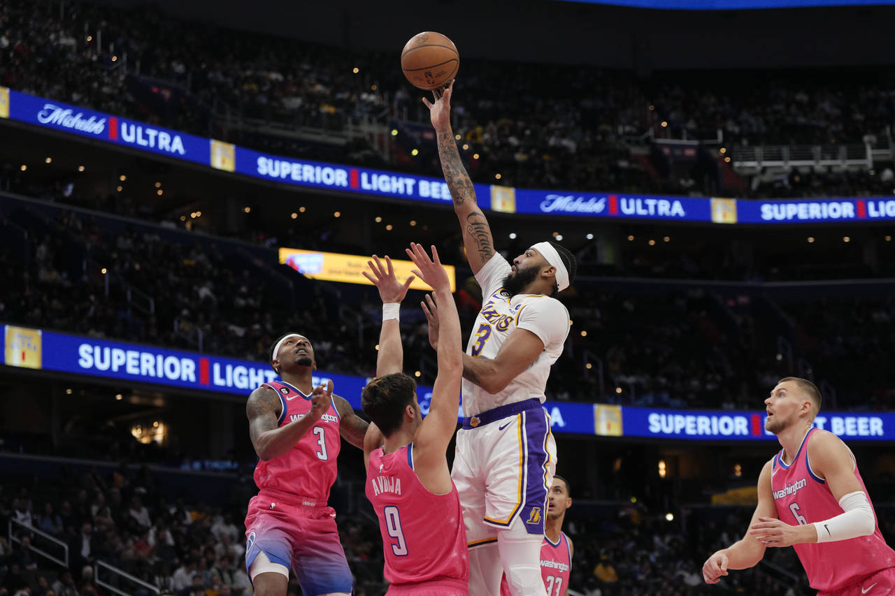 Los Angeles Lakers forward Anthony Davis, center, scores as Washington Wizards guard Bradley Beal, ...