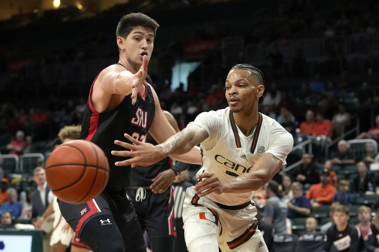 Miami guard Isaiah Wong, right, passes the ball as St. Francis forward Josh Cohen defends during th...