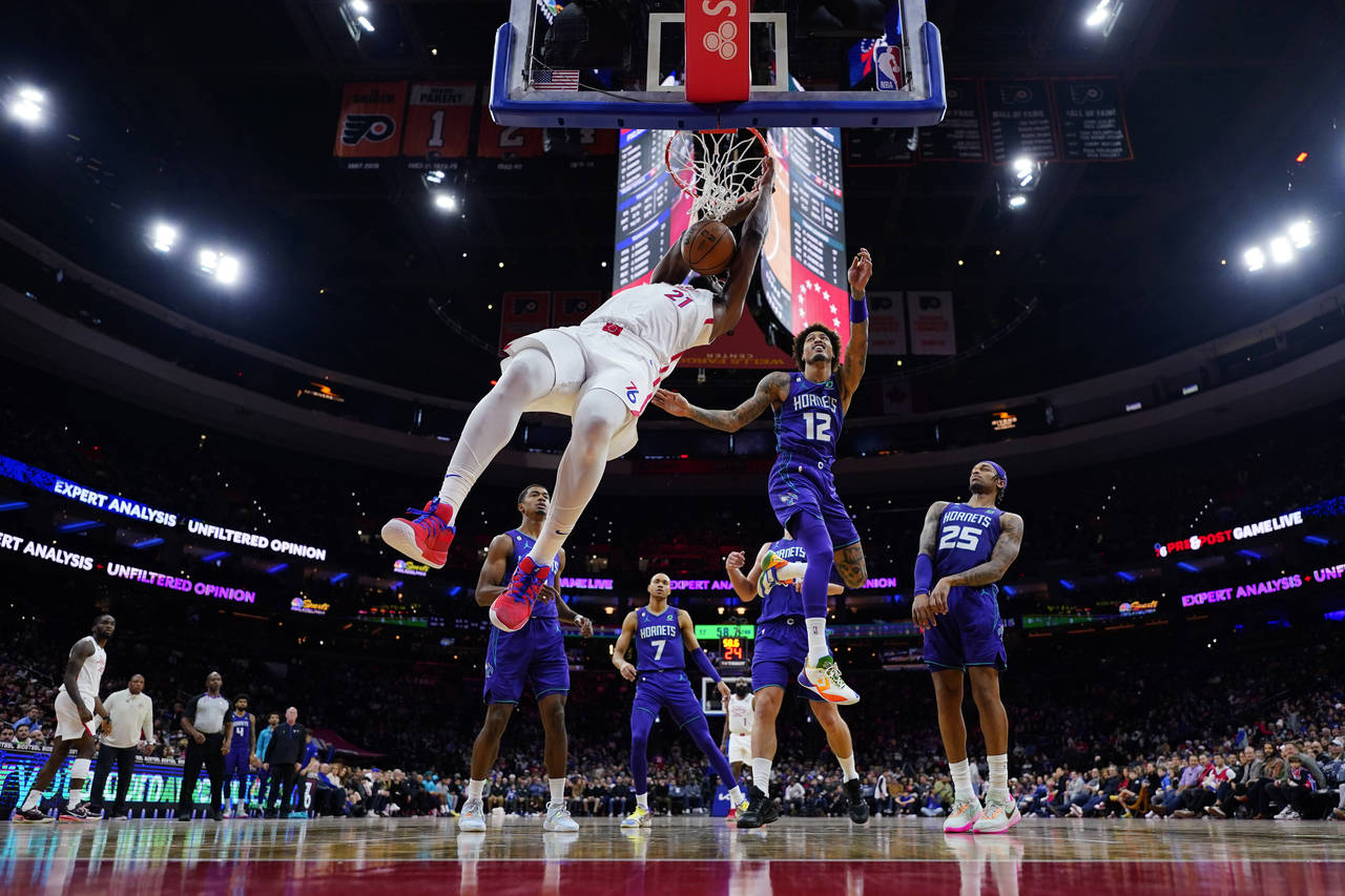 Philadelphia 76ers' Joel Embiid, left, dunks past Charlotte Hornets' Kelly Oubre Jr. during the fir...