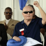 
              FILE -  Boxing referee Mills Lane, pumps his fist while being inducted into the International Boxing Hall of Fame during the annual induction ceremony in Canastota, N.Y., June 9, 2013. Lane, the Hall of Fame boxing referee who was the third man in the ring when Tyson bit Holyfield’s ear, died Tuesday, Dec. 6, 2022. He was 85. Lane had suffered a stroke in 2002 and son Tommy said his father had taken a significant turn for the worse recently before entering hospice care on Friday. (AP Photo/Heather Ainsworth, File)
            