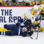 
              Winnipeg Jets' Adam Lowry (17) attempts to play the puck against Nashville Predators' Filip Forsberg (9) during the second period of an NHL hockey game, Thursday, Dec. 15, 2022 in Winnipeg, Manitoba. (John Woods/The Canadian Press via AP)
            