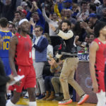 
              Injured Golden State Warriors guard Stephen Curry, middle, reacts after a 3-point basket by guard Ty Jerome (10) during the first half of the team's NBA basketball game against the Portland Trail Blazers in San Francisco, Friday, Dec. 30, 2022. (AP Photo/Jeff Chiu)
            