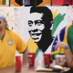 
              A portrait of Pelé is displayed at a Brazilian fan party before the the World Cup round of 16 soccer match between Brazil and South Korea, in Doha, Dec. 5, 2022. The 82-year-old Pelé remained in a hospital in San Paulo recovering from a respiratory infection that was aggravated by COVID-19, but the news coming from Brazil early Monday was good. (AP Photo/Ashley Landis)
            
